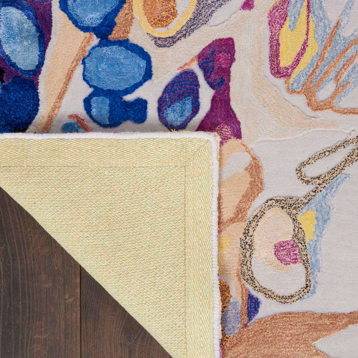 Close-up of a colorful area rug with a portion turned back to reveal the underside.