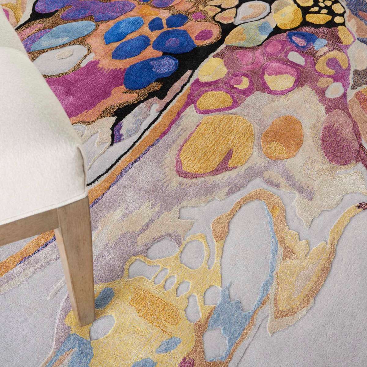 Colorful abstract patterned area rug with a chair leg in the corner