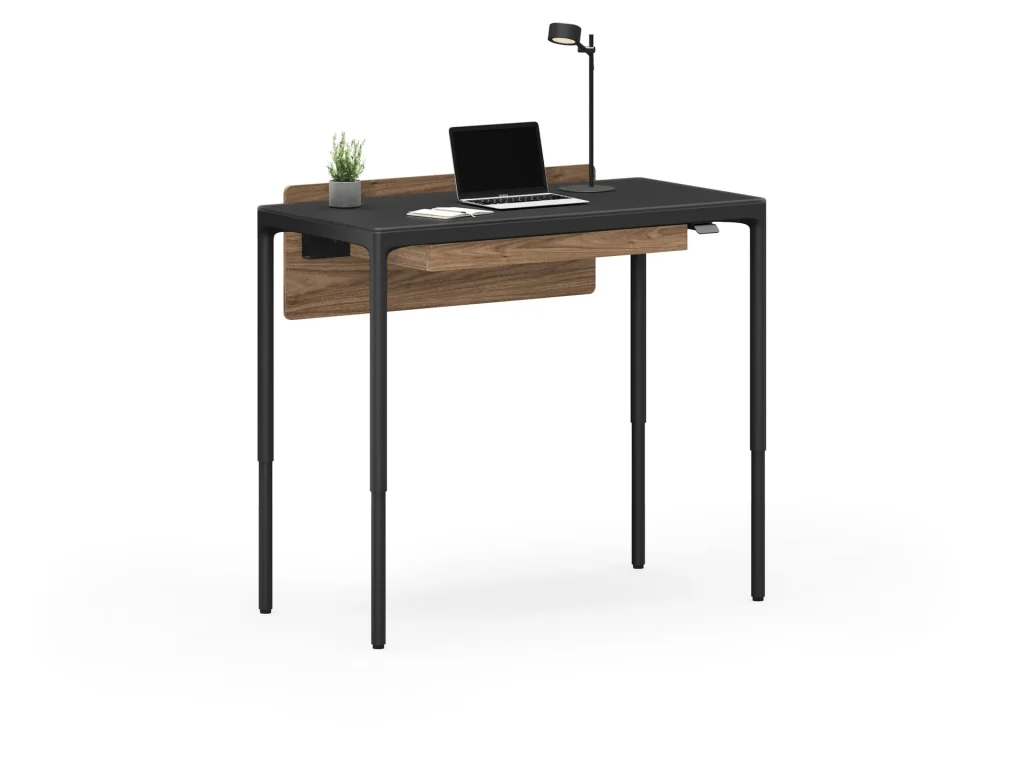 A modern black and wood desk with a laptop, lamp, and small plant.
